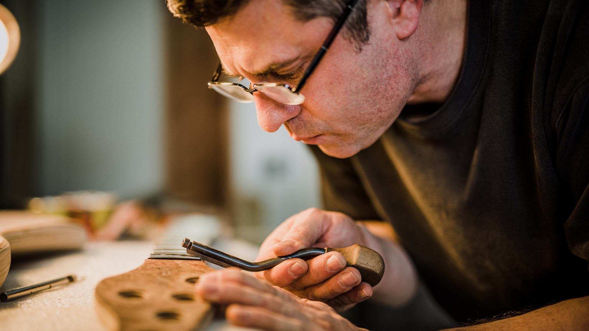 Luthier with detail work on frets